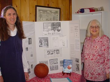 #9b Susan Steere and Mary Ellen Westlake by the John Family display – featuring the book written by Gene Johnson’s son, Jim Johnson: A COACH AND A MIRACLE